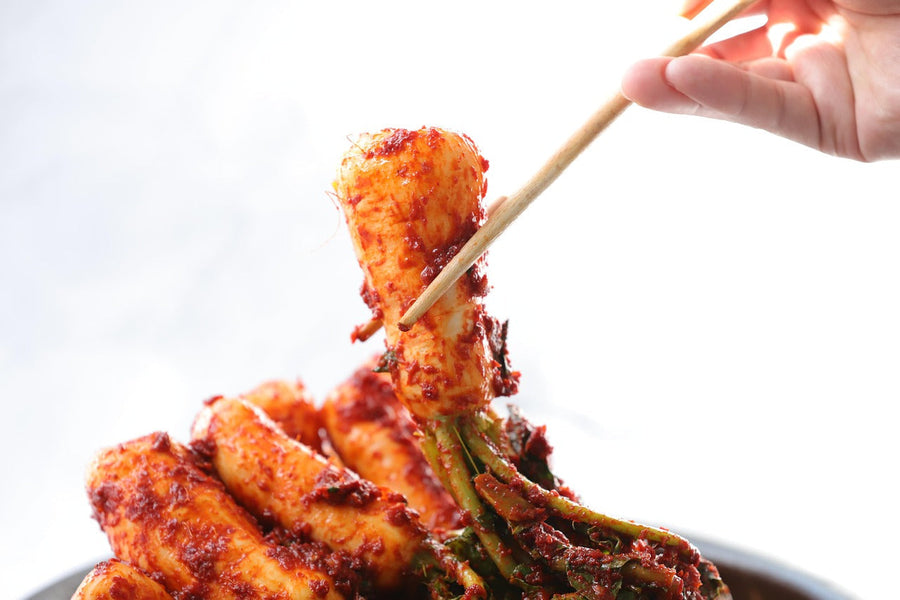 Kimchi die met eetstokjes uit een kom wordt gepakt